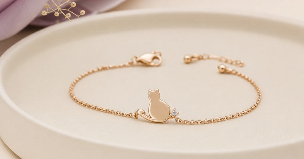 シャンパンゴールドの猫モチーフブレスレットをアイボリーの背景に静かに配置した高級感のあるジュエリー写真
